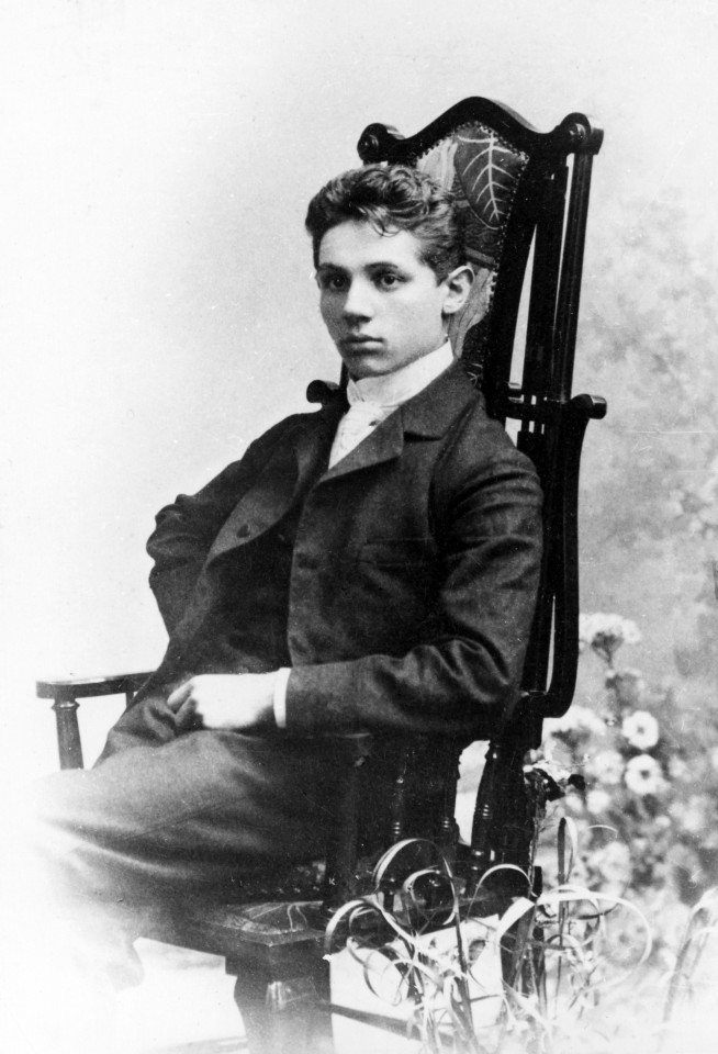 Czarno białe zdjęcie z chłopcem siedzącym na krześle.