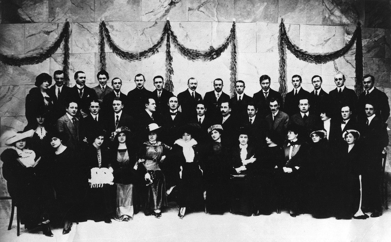 Czarno białe zdjęcie z grupą ludzi ustawionych w trzy rzędy.