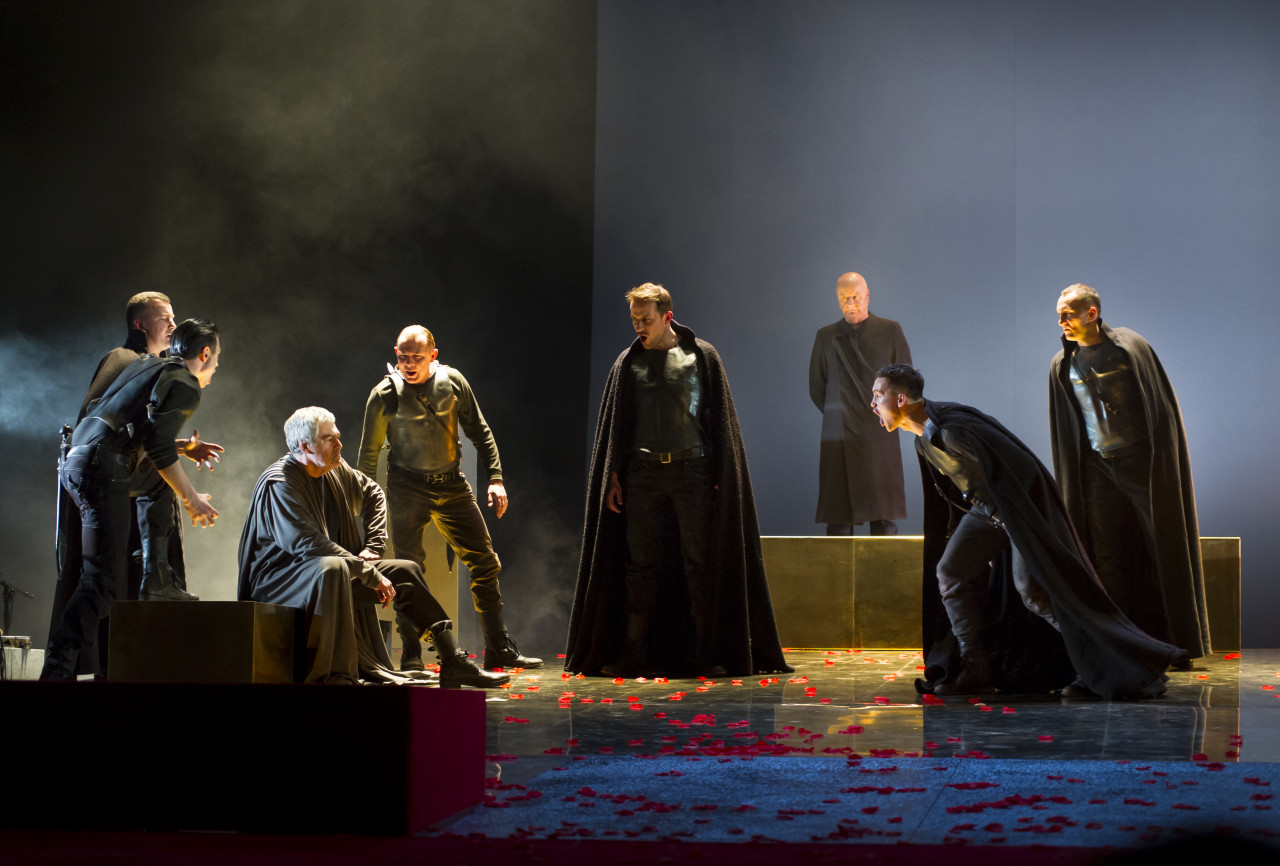 Na kolorowym zdjęciu grupa aktorów na scenie pośród scenografii teatralnej spektaklu Irydion.
