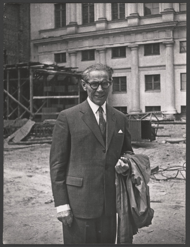 Na czarno-białym zdjęciu Arnold Szyfman na budowie Teatru Wielkiego w Warszawie. Starszy mężczyzna z płaszczem.