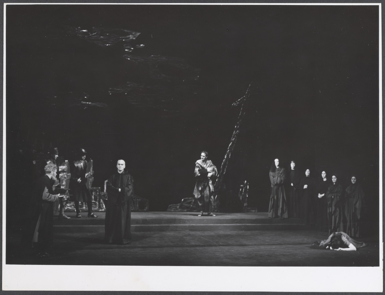 Na czarno-białym zdjęciu grupa aktorów na scenie w rolach podczas spektaklu Irydion.