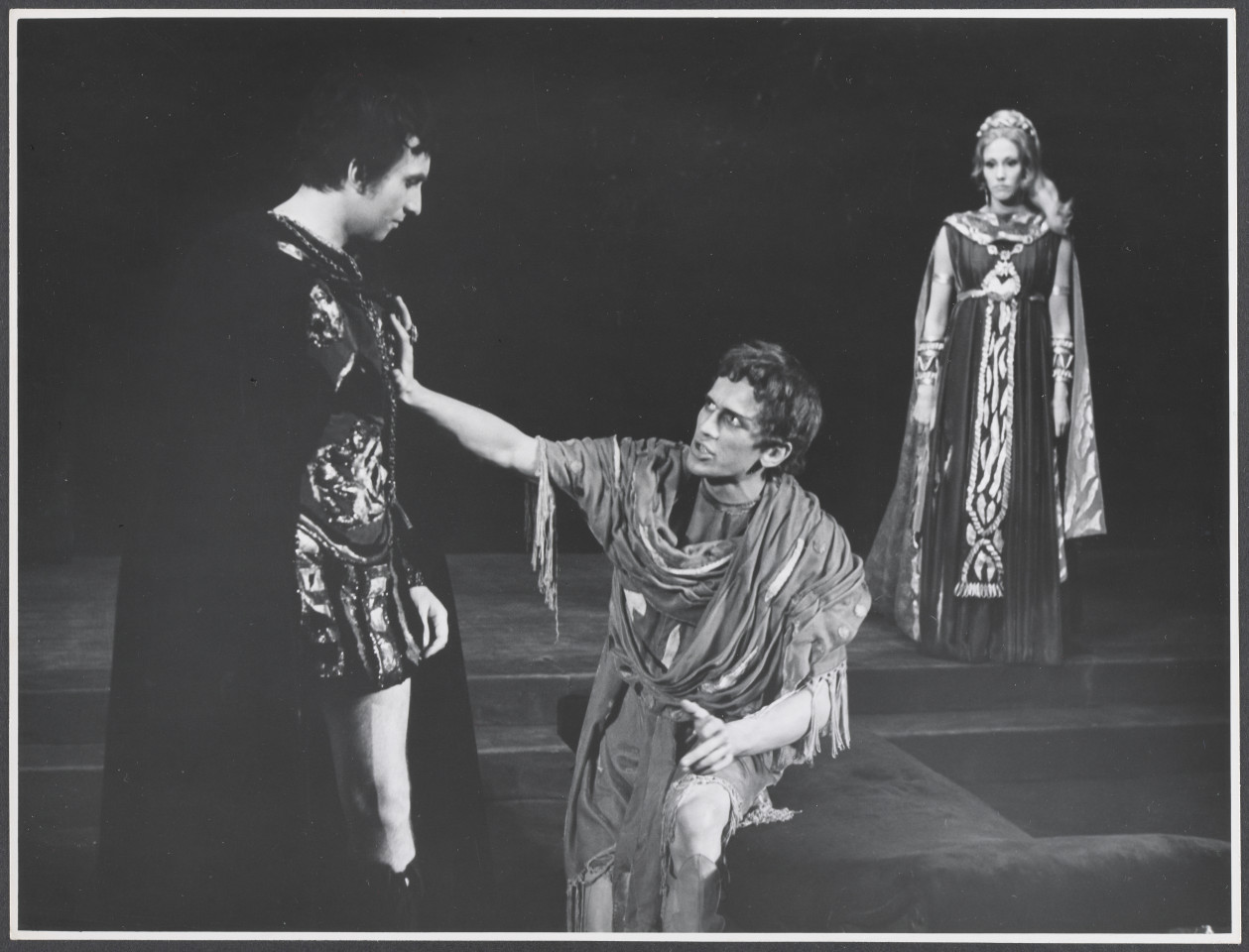 Na czarno-białym zdjęciu trójka aktorów na scenie w rolach podczas spektaklu Irydion.